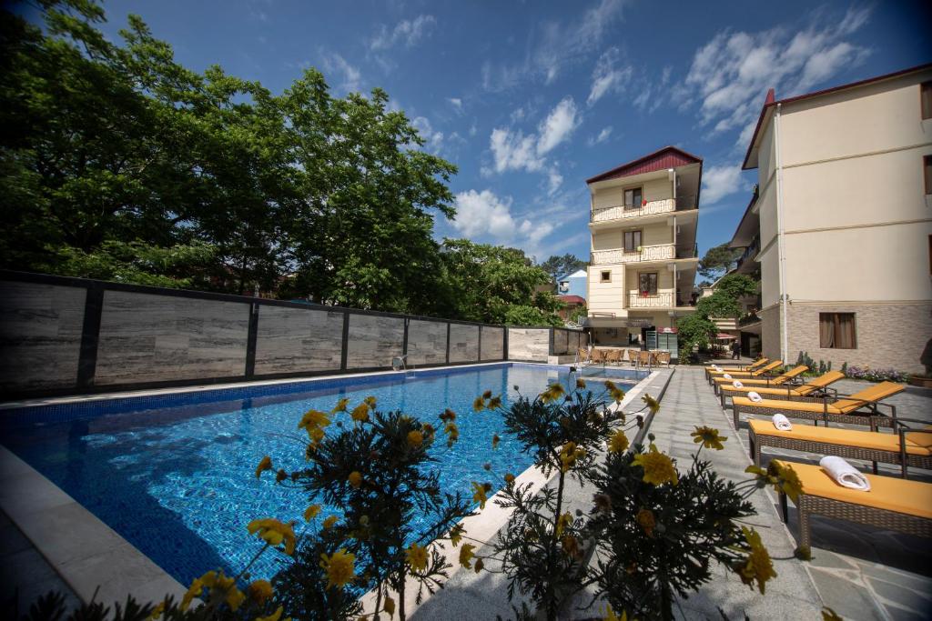 a swimming pool with lounge chairs next to a building at Hotel Chveni Ezo in K'obulet'i