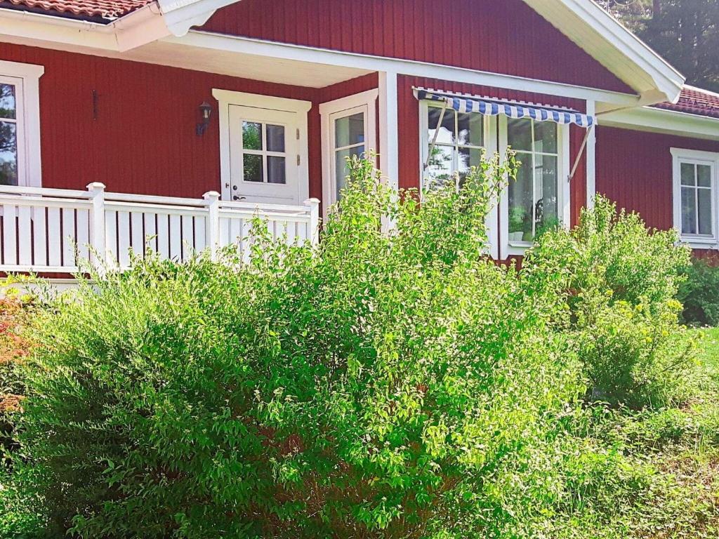 ein rotes Haus mit einer weißen Veranda und Büschen in der Unterkunft Holiday home VäTö in Harg