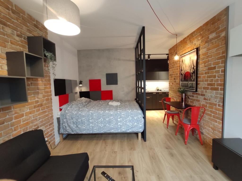 Red wall apartment in the Old Town في غدانسك: غرفة نوم بسرير وجدار من الطوب