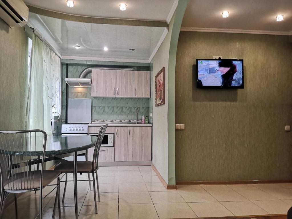 a kitchen with a table and a tv on the wall at Уютная квартира возле CITY Mall in Zaporozhye