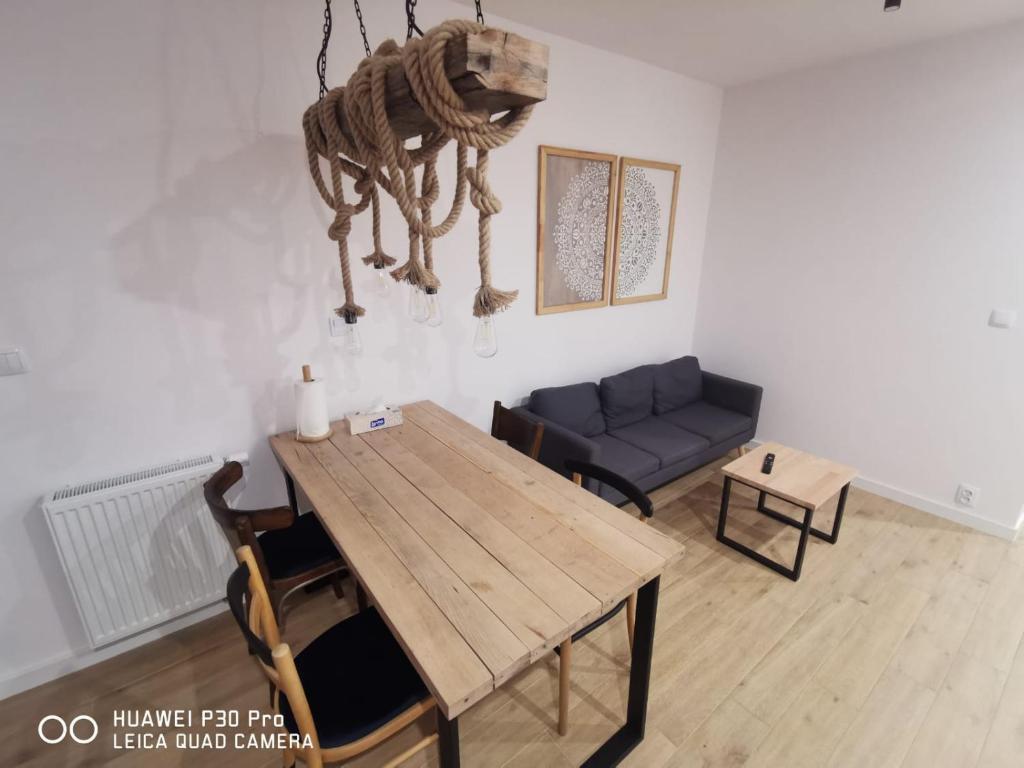 a living room with a wooden table and a couch at Komfortowe pokoje w Gdańsku w pobliżu jeziora i lasu in Gdańsk