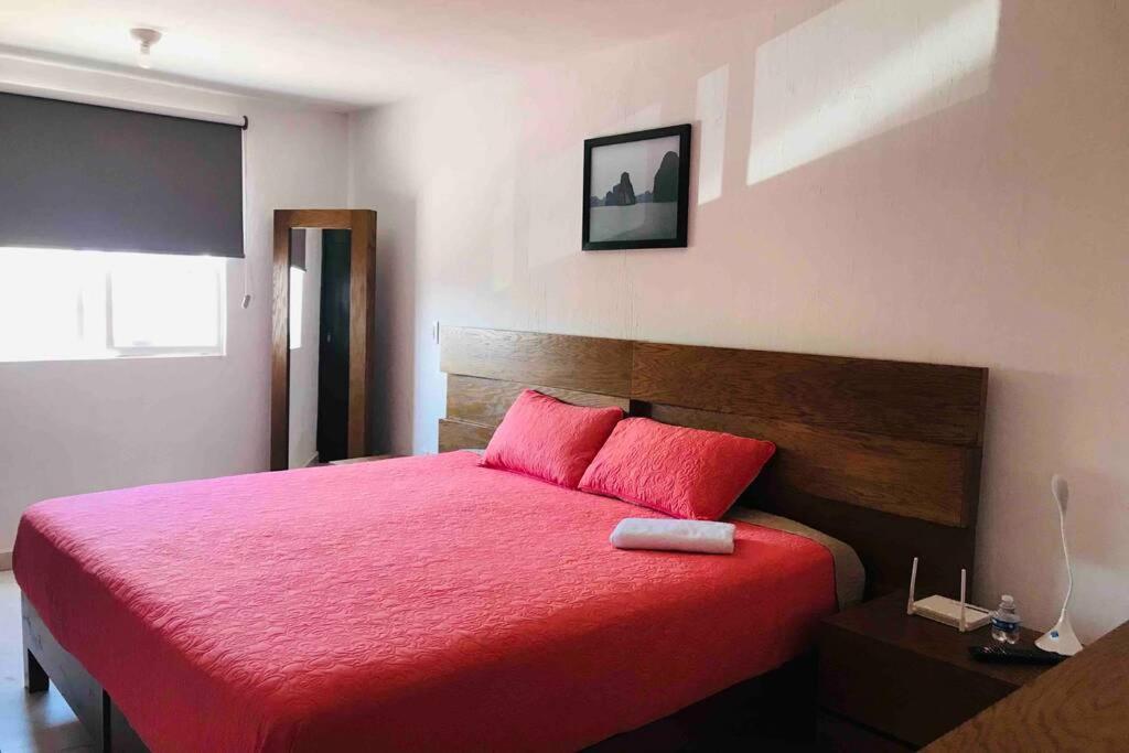 een slaapkamer met een rood bed en een rode deken bij Cerca de plaza galerías, est chivas, Metropolitano in Guadalajara