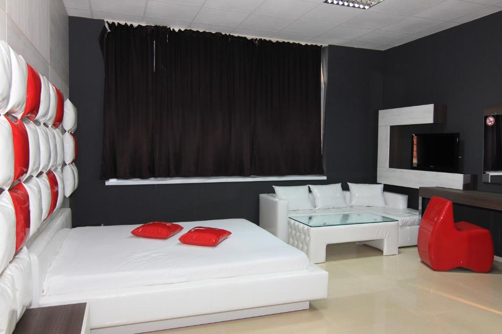 een kamer met 2 witte bedden en een rode stoel bij Bedroom Place Guest Rooms in Ruse