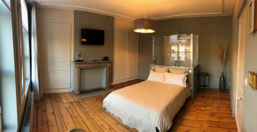 a bedroom with a large bed and a fireplace at Les chambres Berguoises Chambre privée au Cœur de Bergues in Bergues