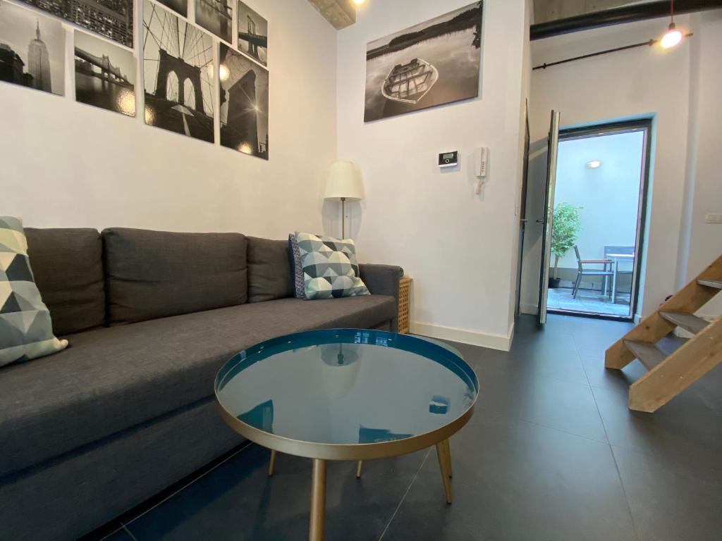 ein Wohnzimmer mit einem Sofa und einem Glastisch in der Unterkunft Modern cozy studio with backyard in Antwerpen