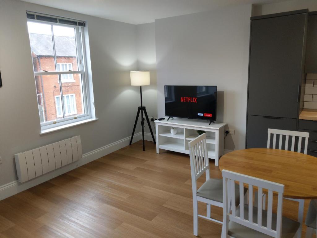 a living room with a dining room table and a television at 27 High Street Apartments in Husbands Bosworth