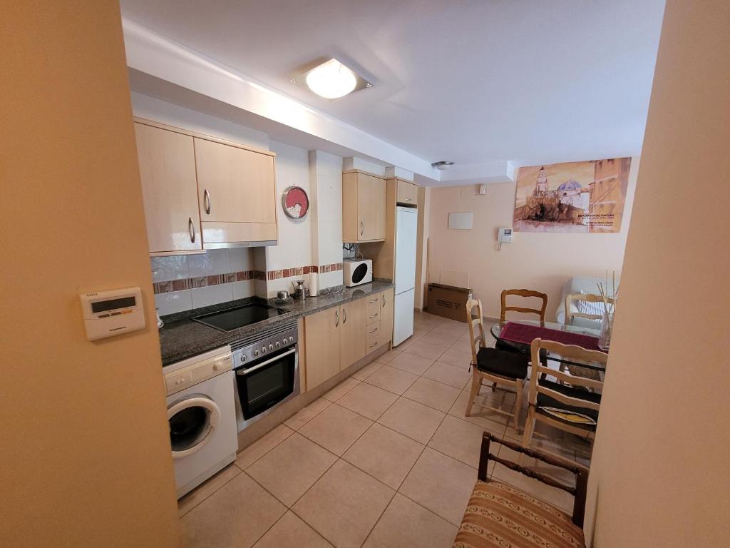una cocina con electrodomésticos blancos, mesa y sillas en Apartamento vacacional Adriana , Montanejos, en Montanejos