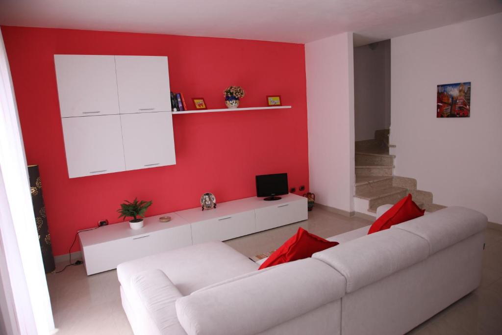 ein Wohnzimmer mit einem weißen Sofa und einer roten Wand in der Unterkunft King's Residence in Balestrate