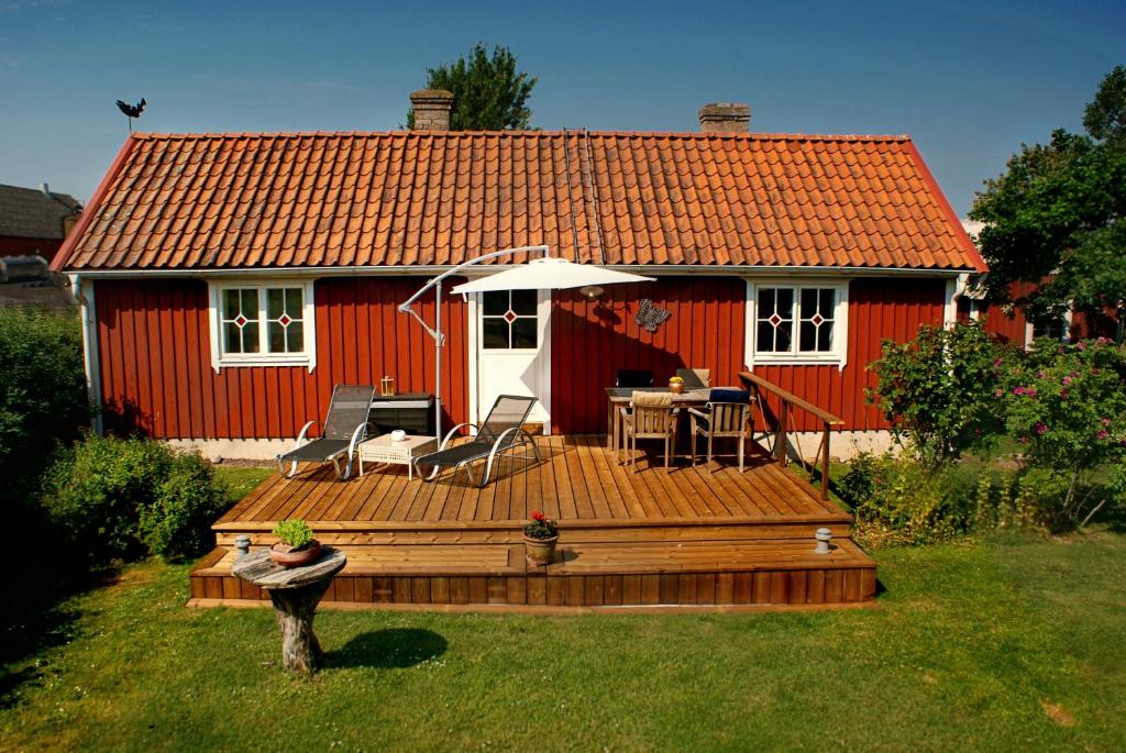 a red house with a wooden deck in front of it at Haus Fjäril in Laxeby