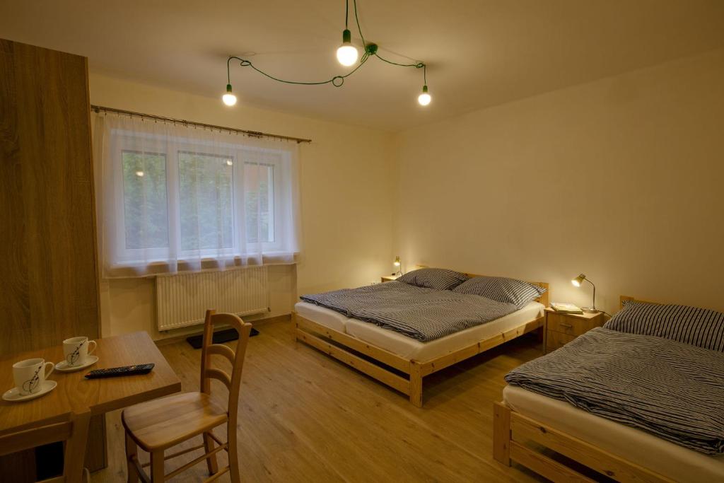 een slaapkamer met 2 bedden, een tafel en een bureau bij Apartmán Žacléř 160 / 11 in Žacléř