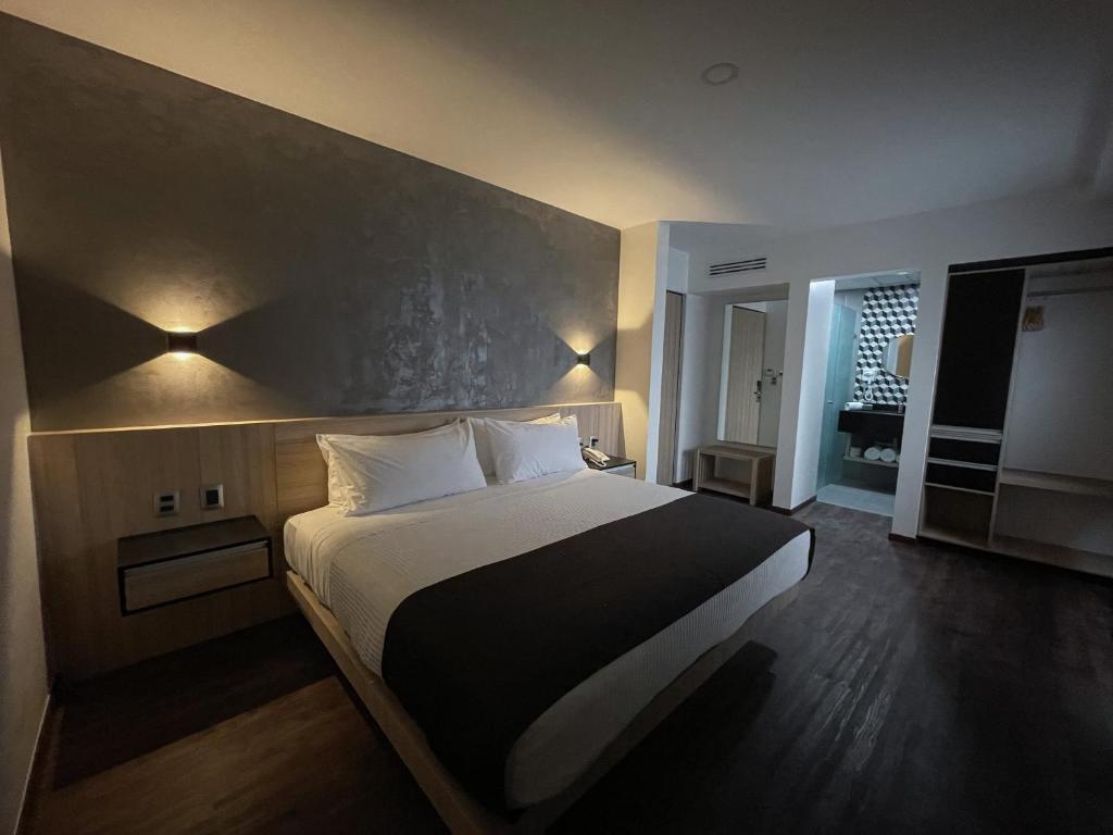 a bedroom with a large bed with two lights on it at Fato Hotel in Querétaro