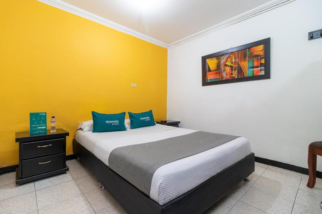 1 dormitorio con cama y pared amarilla en Ayenda Avenida Boyaca, en Bogotá