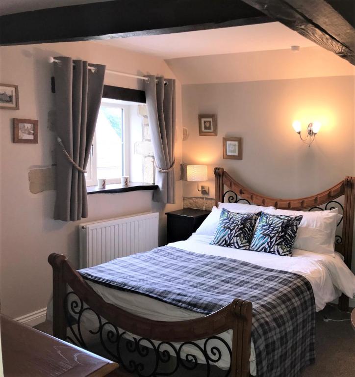 ein Schlafzimmer mit einem Bett mit einer blauen und weißen Decke in der Unterkunft Cotswold Merrymouth Inn in Bourton on the Water