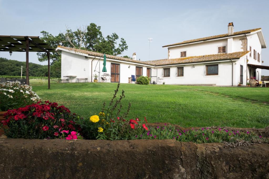 a large white house with flowers in the yard at Agriturismo il Poggio in Vetralla