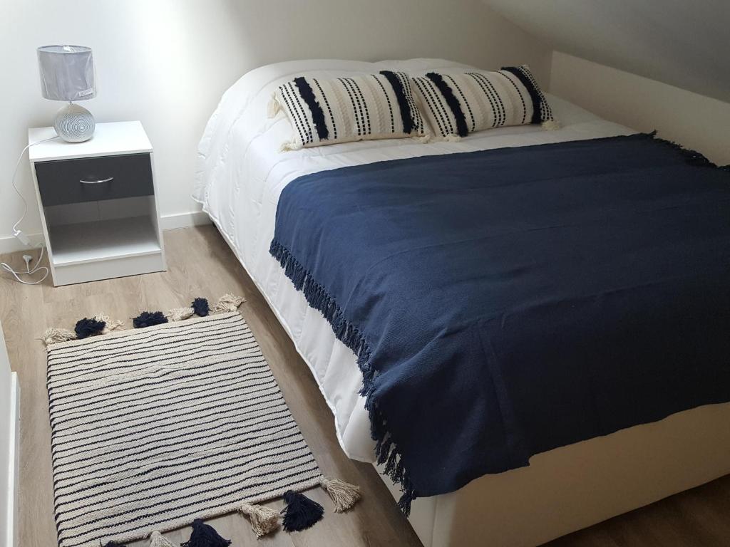 1 dormitorio con 1 cama con manta azul y mesita de noche en Charmante Maison Cosy à Villabé-Hyper Centre-Gare-WIFI en Villabé