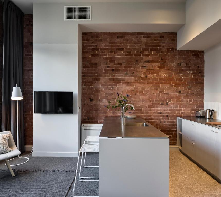 a kitchen with a sink and a brick wall at The Chamberson in Dunedin