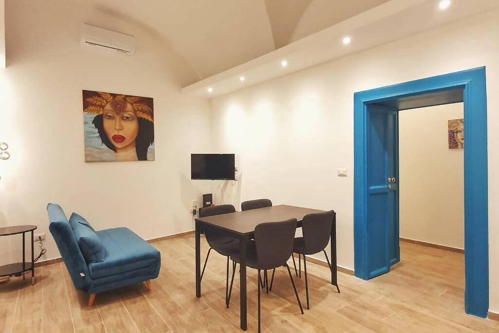 jadalnia ze stołem i krzesłami oraz niebieskimi drzwiami w obiekcie BluMaison - charming holiday home w Katanii