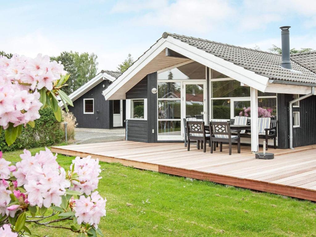 una casa con una gran terraza de madera con flores rosas en Holiday home Væggerløse CLXXVIII, en Bøtø By