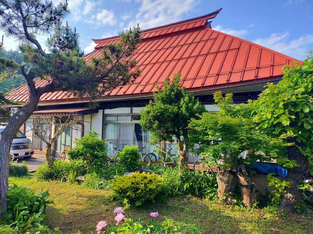 uma casa com um telhado vermelho e algumas árvores e flores em Madarao Farm em Nakano