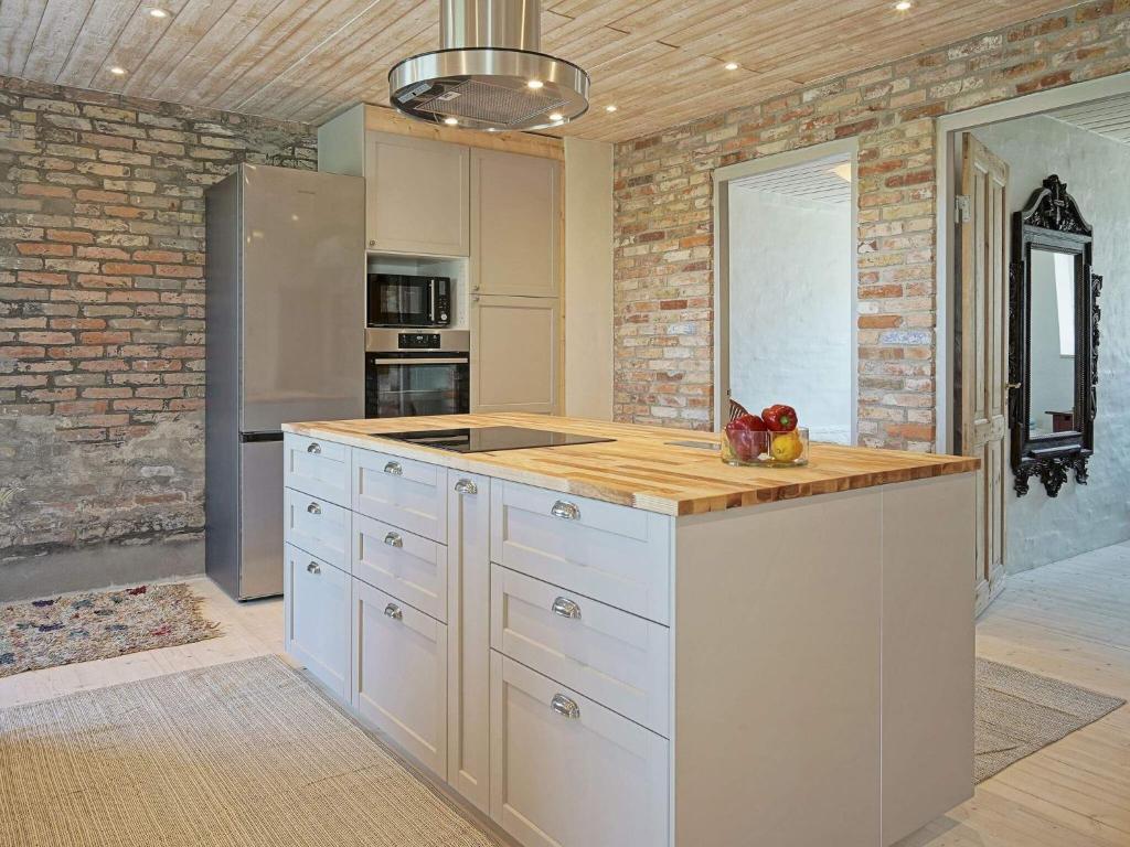 a kitchen with white cabinets and a brick wall at 6 person holiday home in Svaneke in Svaneke