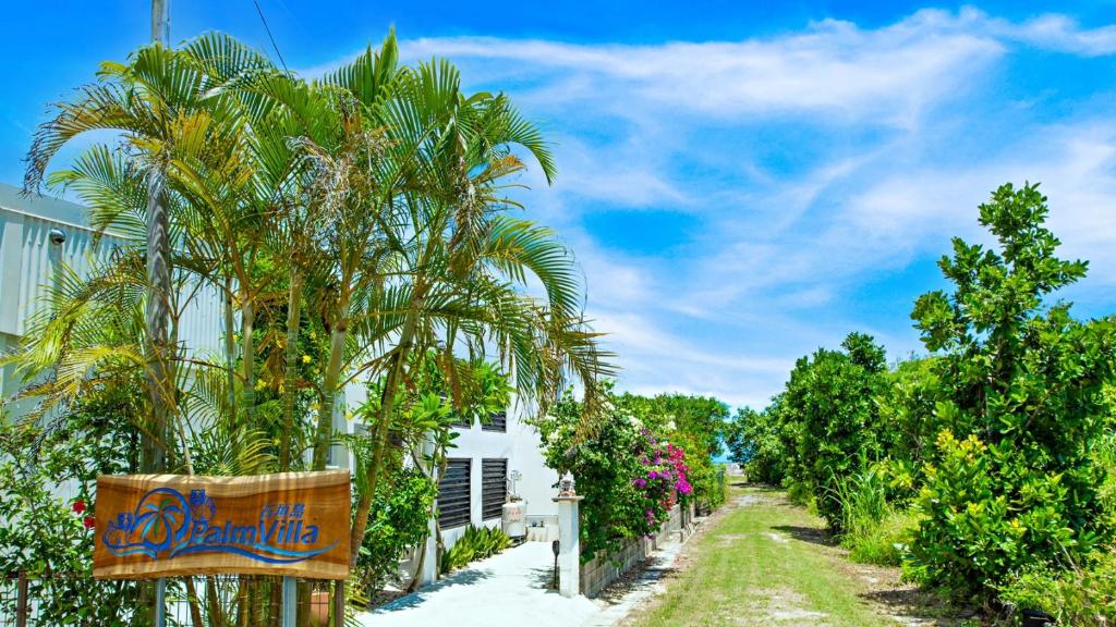 una palmera junto a un edificio blanco en Palm Villa Ishigakijima fusu en Isla Ishigaki
