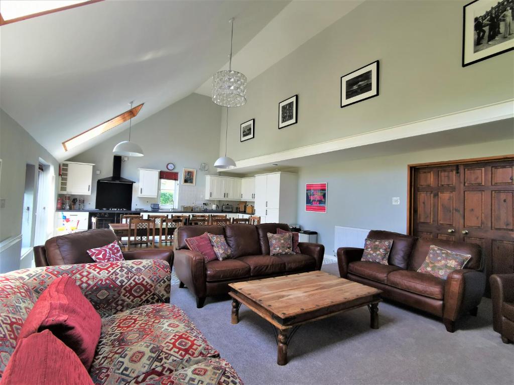 a living room with couches and a coffee table at Wellstone Cottages - Coach House in Pembrokeshire