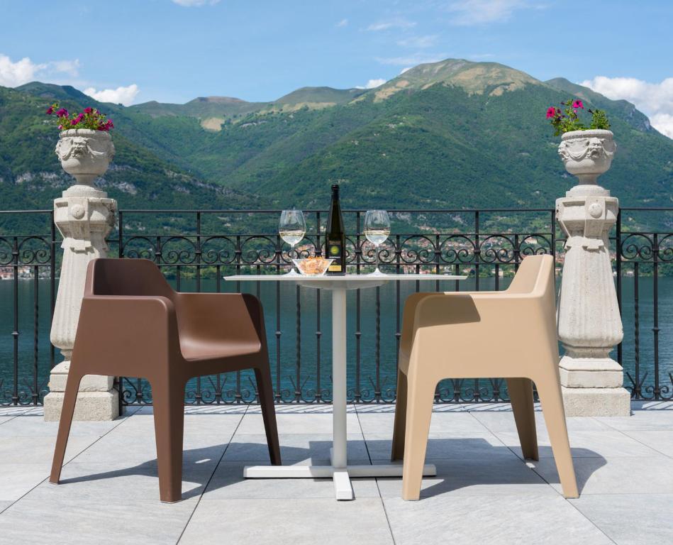 2 Stühle und ein Tisch auf einem Balkon mit Bergblick in der Unterkunft Hotel Helvetia in Lezzeno