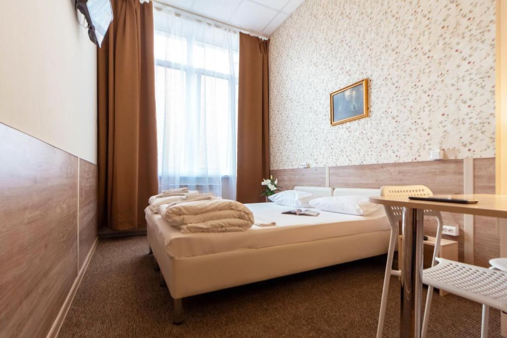 um quarto com uma cama, uma mesa e uma janela em Hotel Kolos em Tyumen