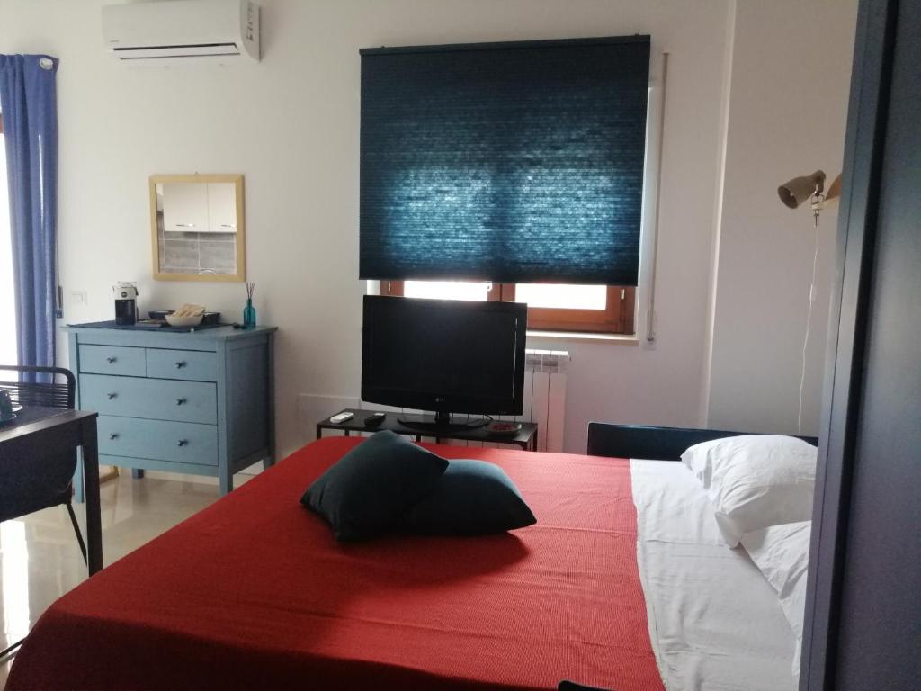 um quarto com uma cama com um cobertor vermelho e uma televisão em Blu Home em Crotone