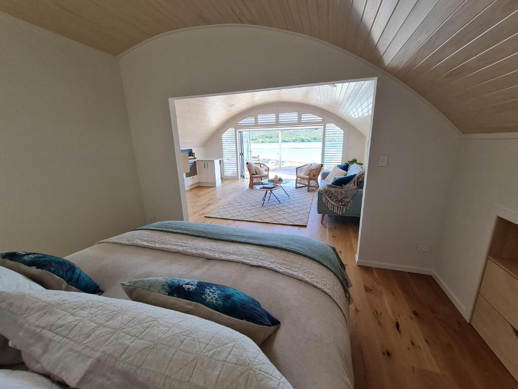 a bedroom with two beds and a living room at The Boatshed, Luxury Waterfront Accommodation in Raglan