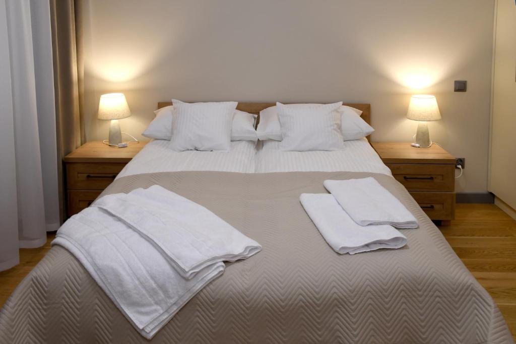 een slaapkamer met een groot bed met witte lakens en kussens bij APARTAMENT KOTLINKA in Jasło