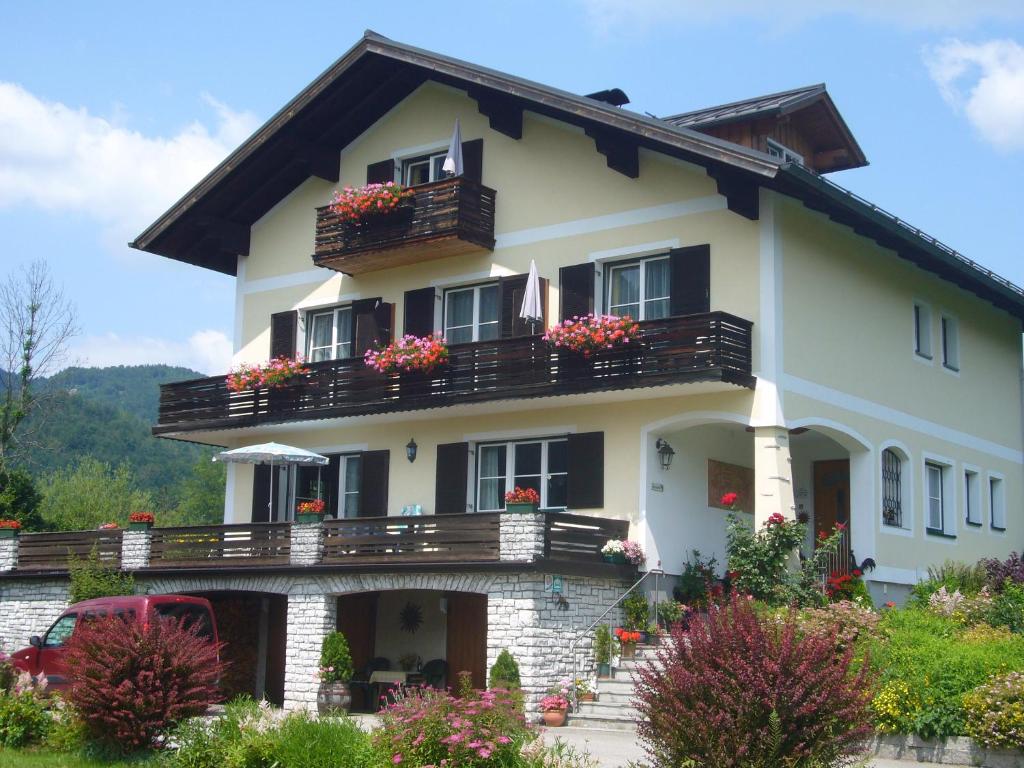 ein großes weißes Haus mit Blumen auf den Balkonen in der Unterkunft Ferienwohnungen Haus Peer in Bad Goisern