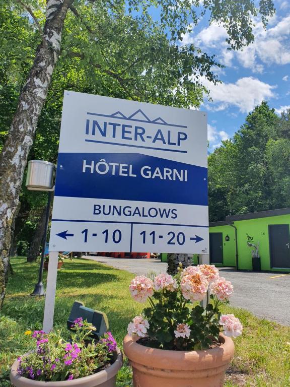 Motel - Hôtel "Inter-Alp" à St-Maurice في سانت موريس: علامة على حديقة الفندق مع الزهور في الأواني