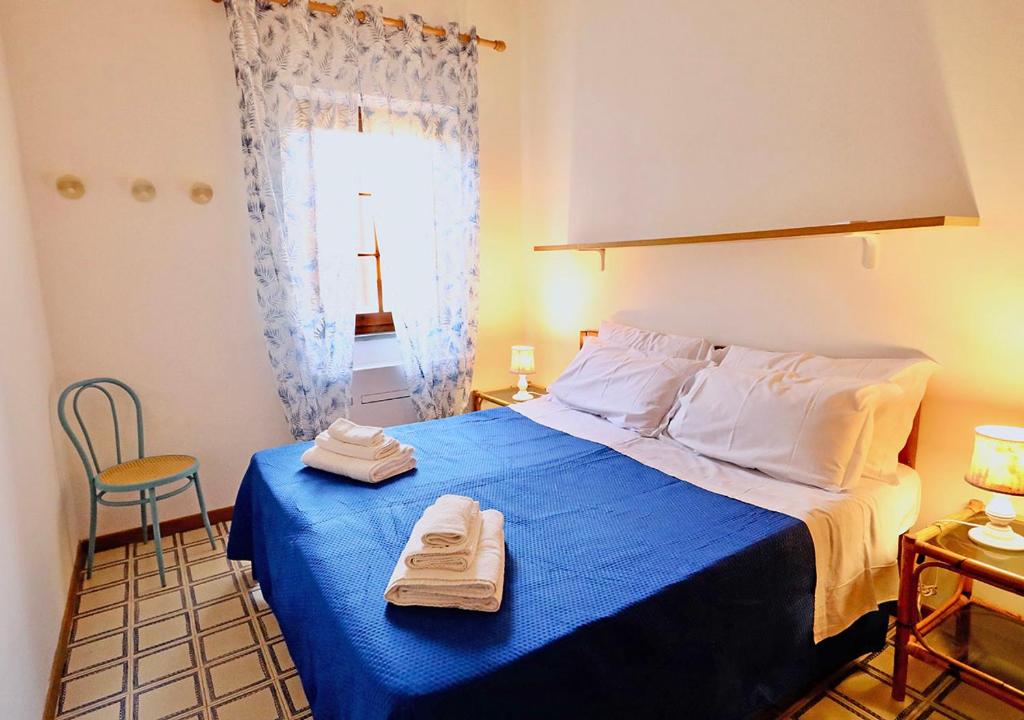 a bedroom with a blue bed with two towels on it at Casa Nanni - 50 mt dal mare in Stintino