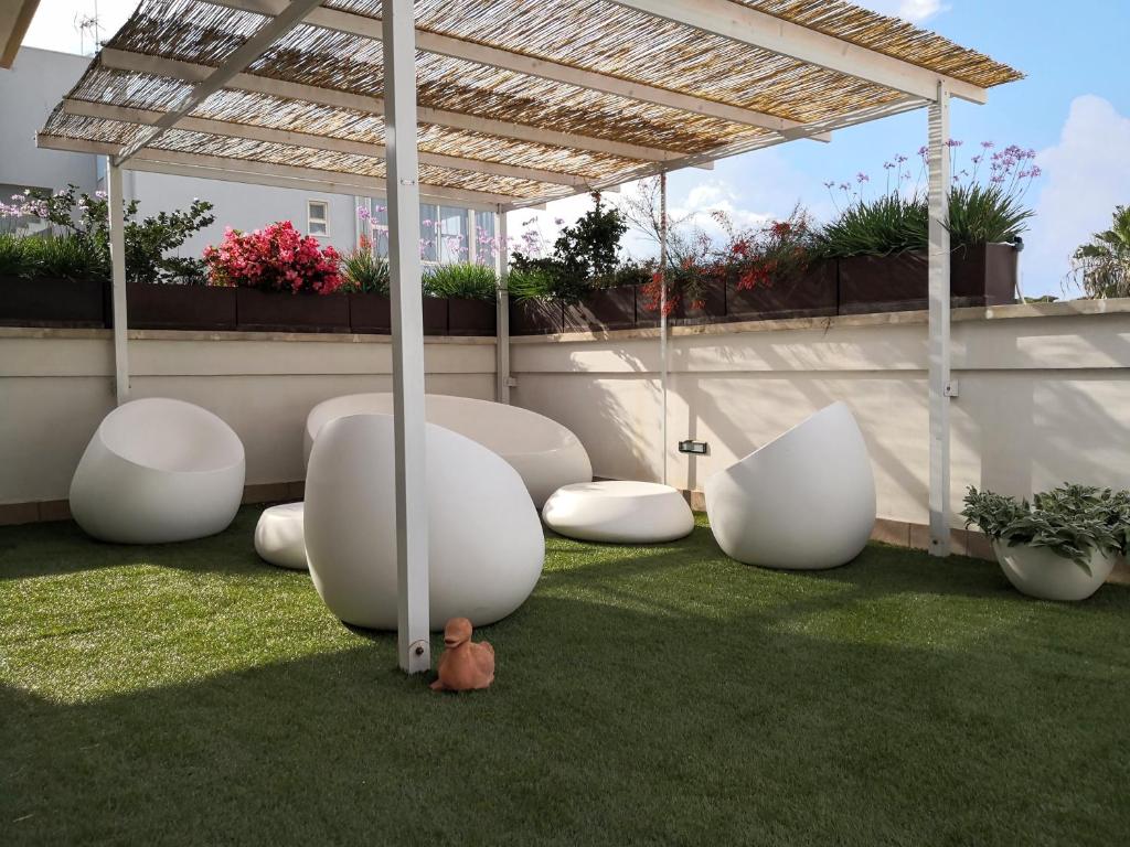 a patio with white chairs and a pergola at La Casa del Turista in Gallipoli