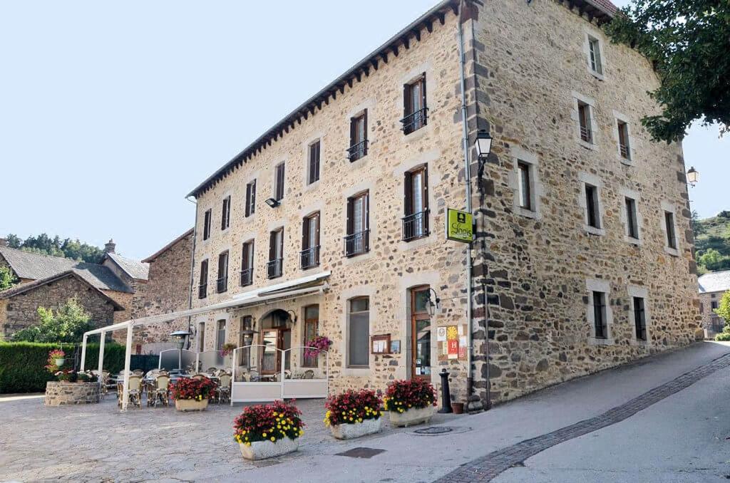 a large stone building with flowers in front of it at Logis Hôtel Auberge de l'Allagnonette in Saint-Poncy