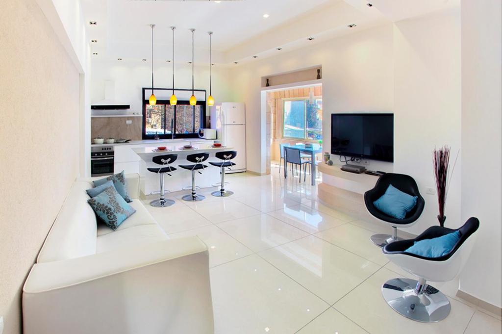 una gran cocina blanca con sillas negras y TV en Luxury apartment in the heart of the German colony, en Jerusalén