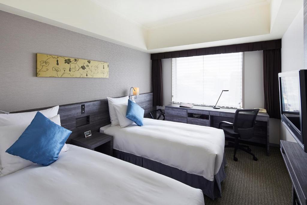 a hotel room with two beds and a desk at ANA Crowne Plaza Kanazawa by IHG in Kanazawa