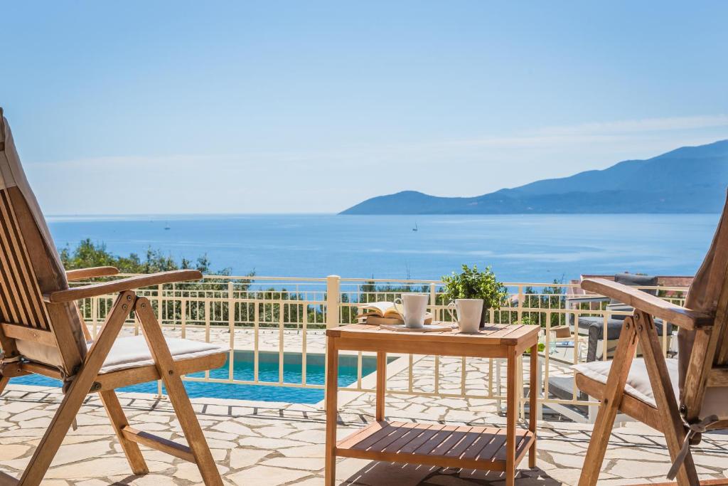 patio con sedie, tavolo e piscina di Villa Irida a Ayia Evfimia