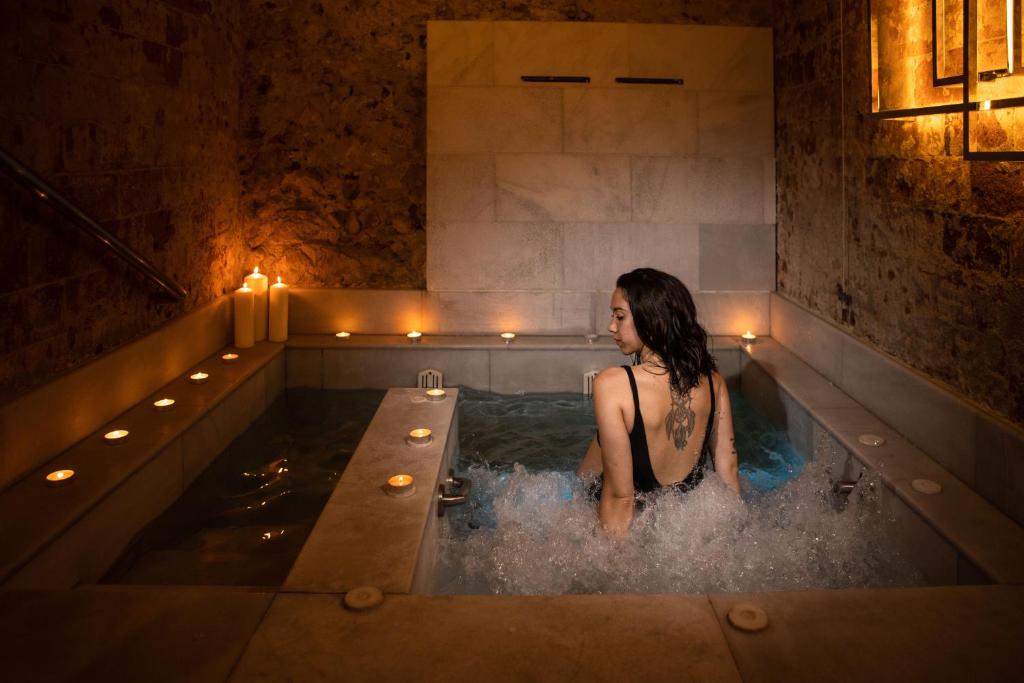 una donna in una vasca da bagno con luci di RVHotels Broquetas Spa Termal a Caldes de Montbui