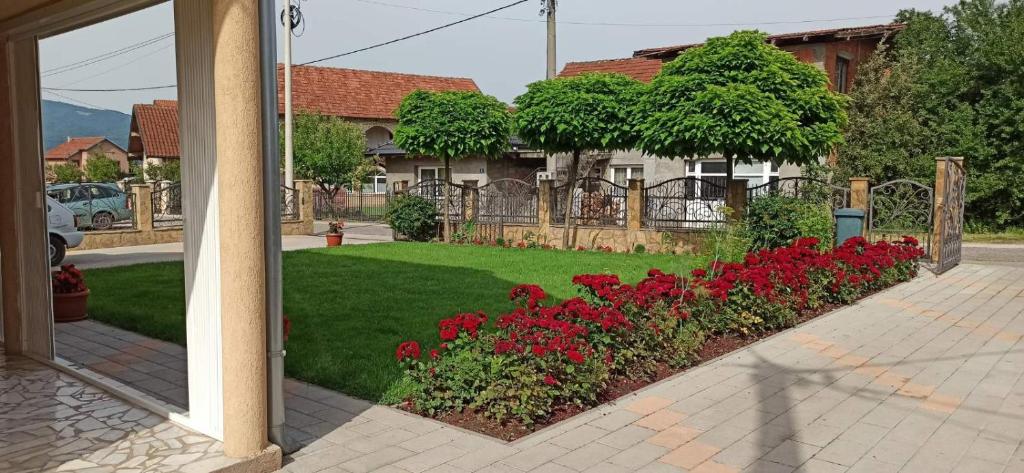una casa con un jardín con flores rojas en un patio en Vila Nikola & Aleksa en Vrnjačka Banja