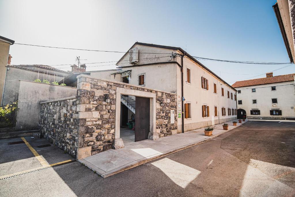 a stone building with a door in a parking lot at Guesthouse Muha in Lipica