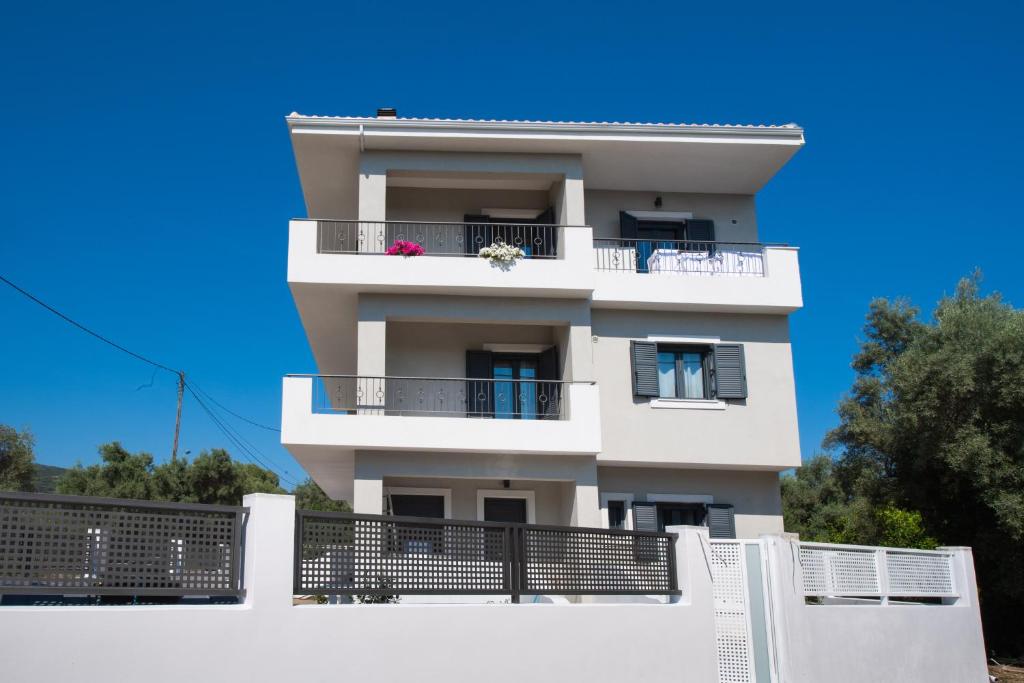 a white building with balconies and a blue sky at Melina apartments in Lefkada