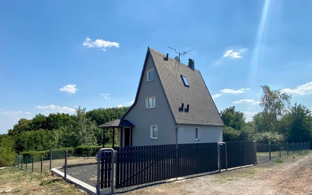 uma casa com um telhado de gambrel com uma cerca preta em Chata v zátoce - Nechranice em Kadaň