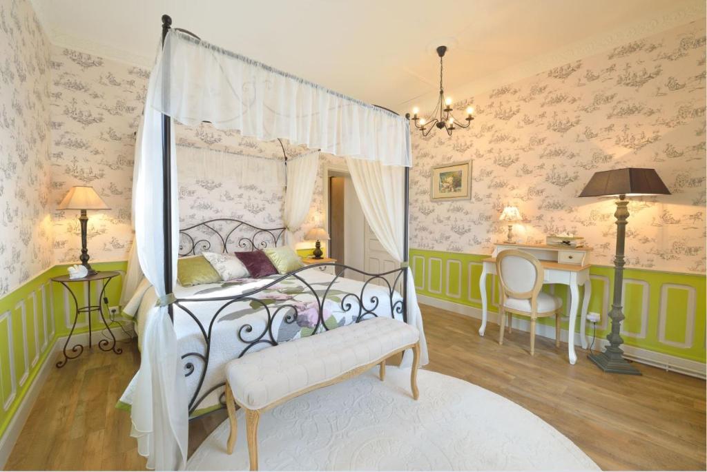 - une chambre avec un lit à baldaquin et un bureau dans l'établissement Le Château de Vernières, à Talizat