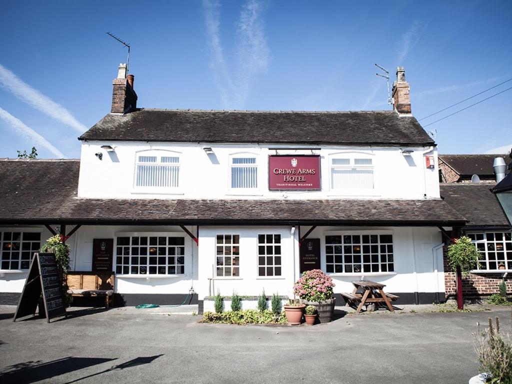 a white building with a picnic table in front of it at The Crewe Arms Hotel in Crewe