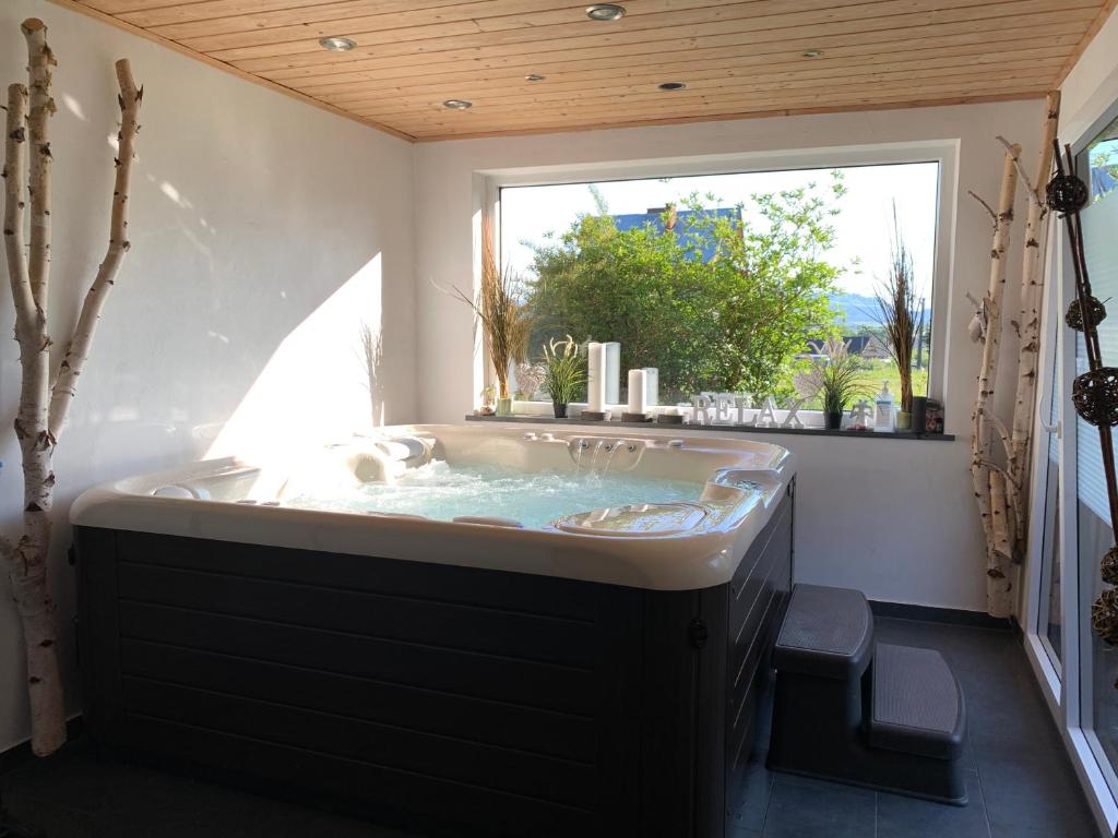 eine große Badewanne in einem Zimmer mit Fenster in der Unterkunft Kapi-Spa Pokoje i Apartamenty in Kluszkowce