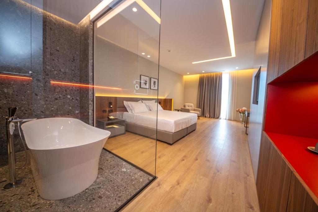 un bagno con vasca e un letto in una camera di Fiore Hotel a Kavajë