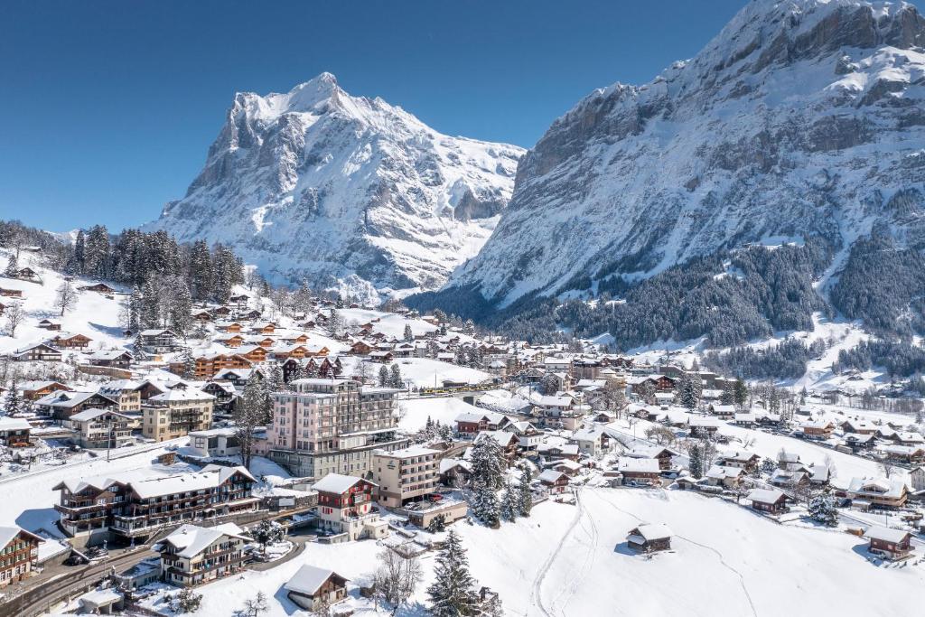 a town covered in snow with a mountain in the background at Belvedere Swiss Quality Hotel in Grindelwald