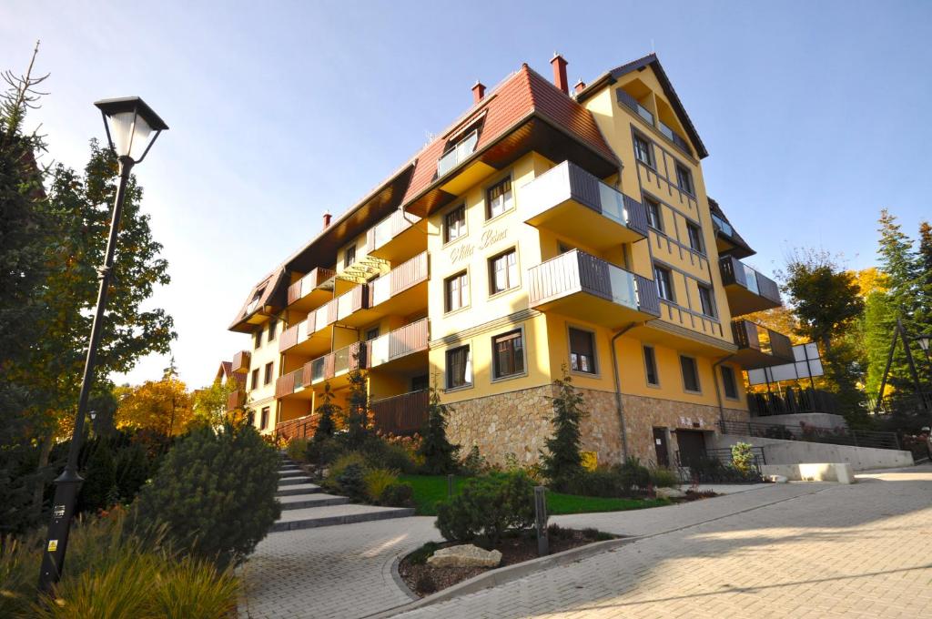 ein großes gelbes Gebäude an der Straßenseite in der Unterkunft Apartament harmonic aparts in Polanica-Zdrój